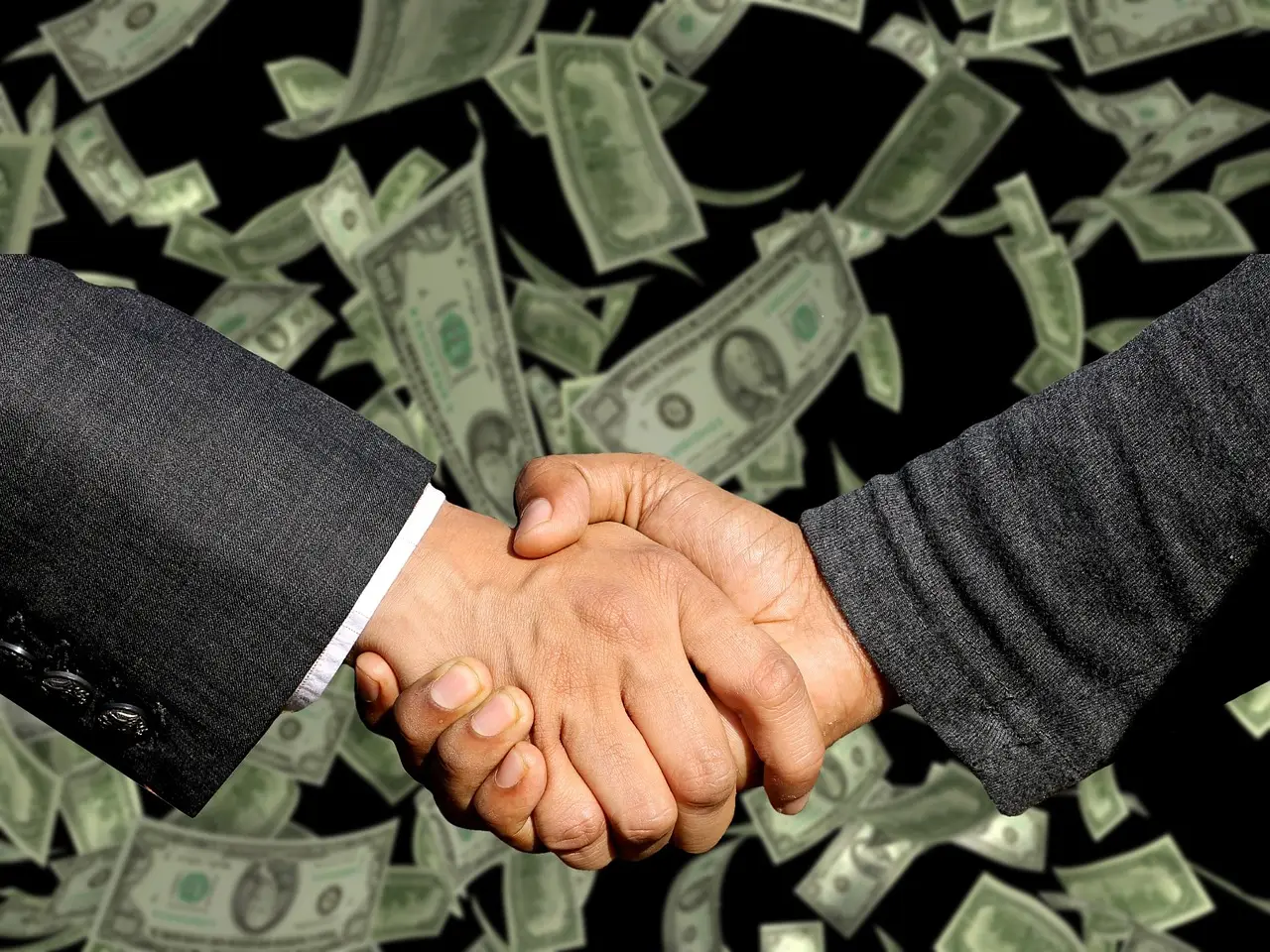 Two hands in dark suit sleeves clasped in a handshake against a backdrop of falling dollar bills