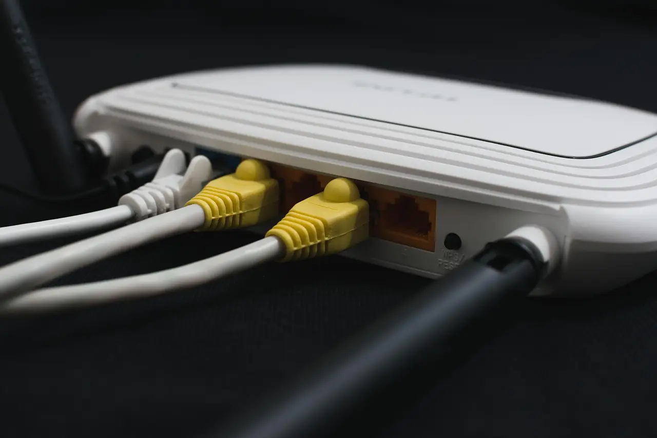 A white home Wi-Fi router with yellow Ethernet cables plugged into its ports