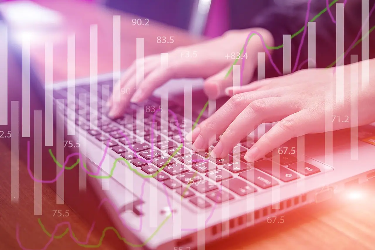 Close-up of hands typing on a laptop keyboard with a translucent data-chart overlay