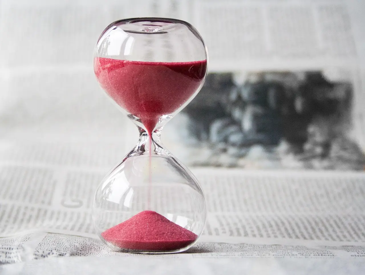 An hourglass with sand running through it against a dark background