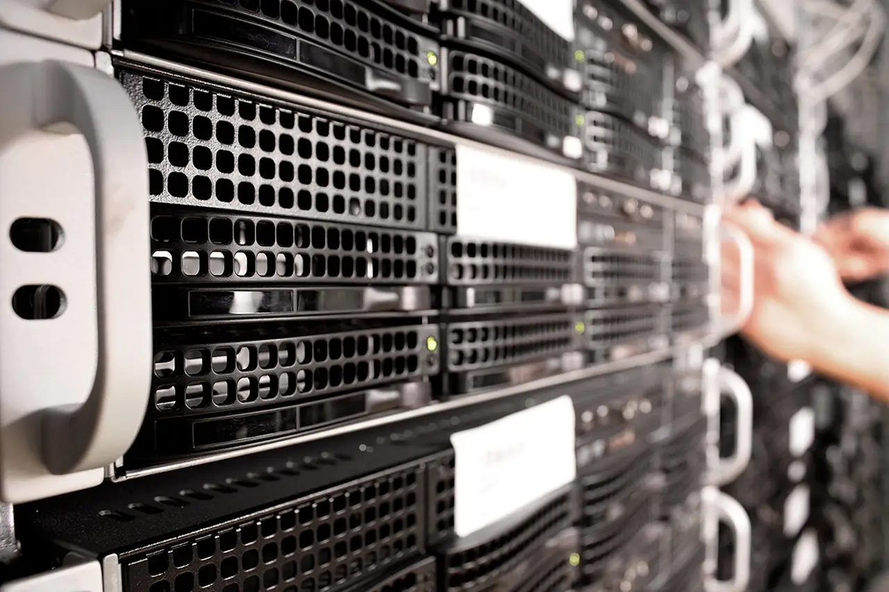 Close-up row of rack-mounted servers with a hand reaching toward one unit's pull handle