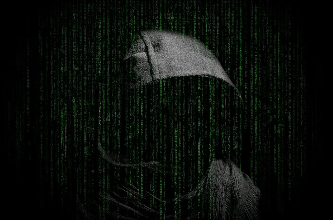 A person typing at a computer in the dark.