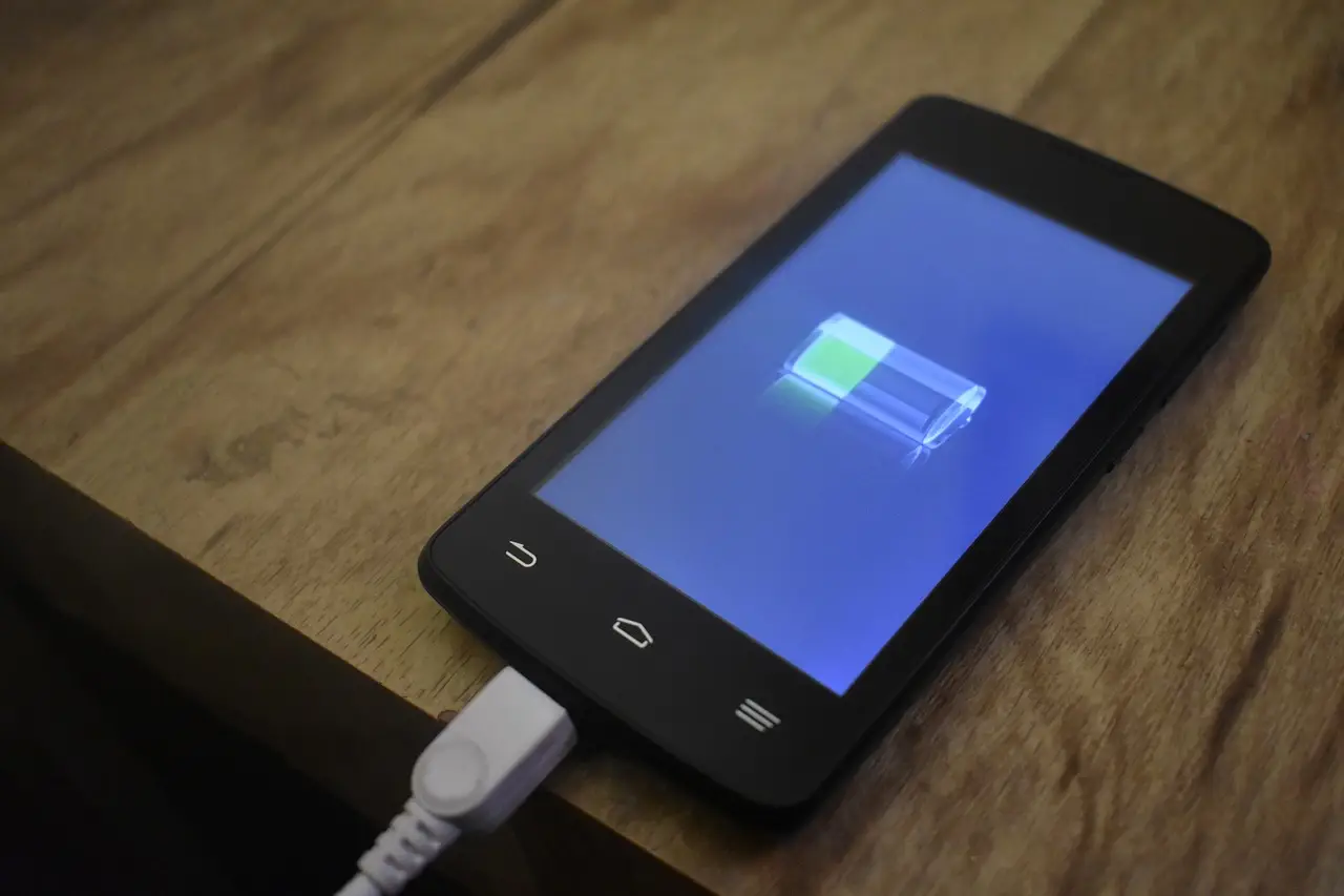 A smartphone charging on a desk