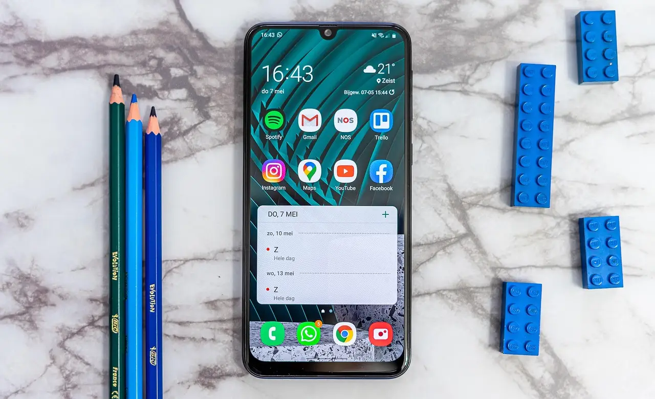 A Samsung Galaxy phone lying screen-up on a desk with the Settings menu open next to a USB-C cable.