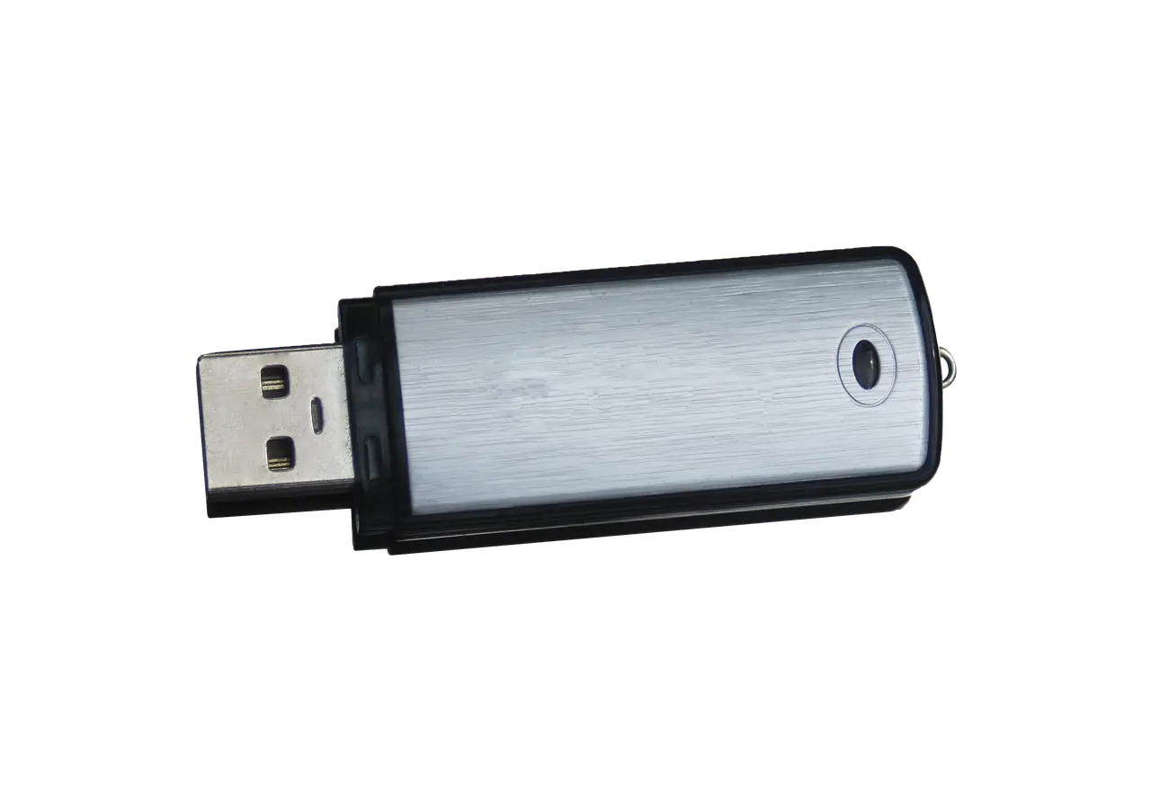 A USB flash drive lying beside a computer, its metal connector exposed