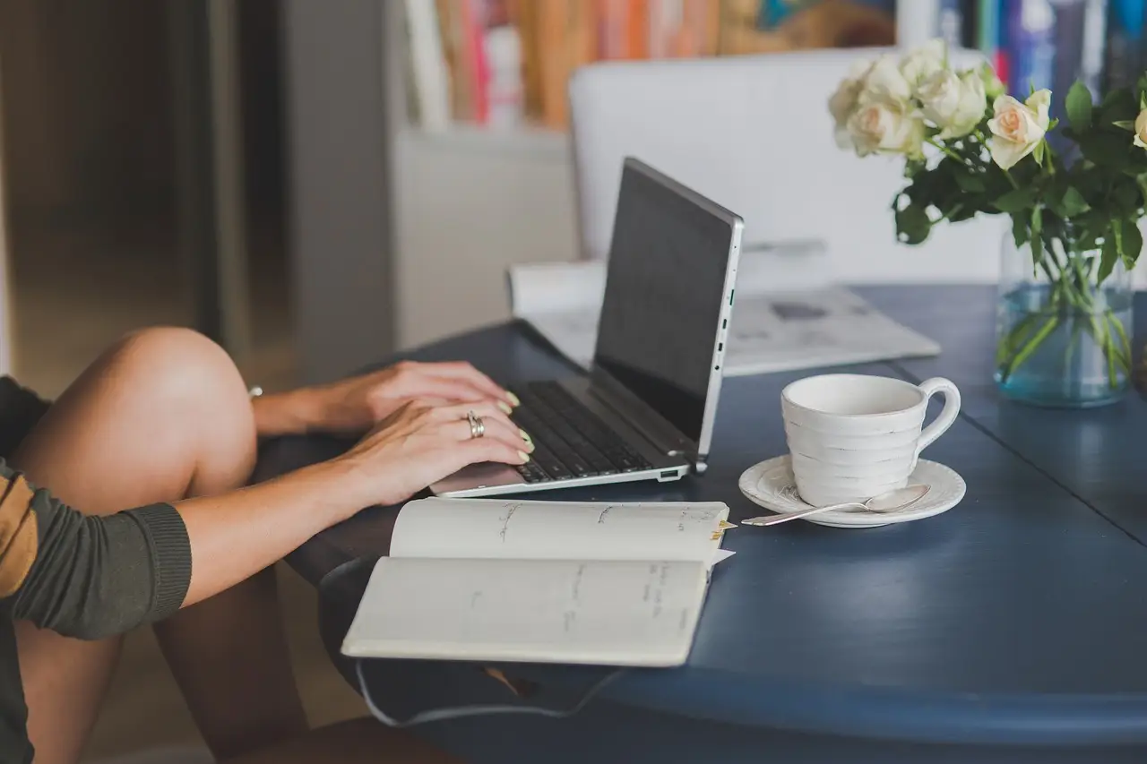 A frustrated person at a laptop in a home office, rubbing their temples.