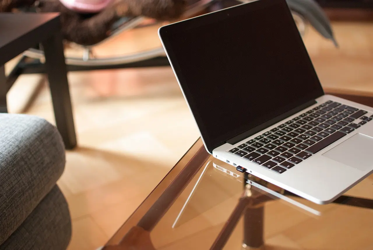 A frustrated office worker staring at a laptop showing a stalled spreadsheet on a wooden desk.
