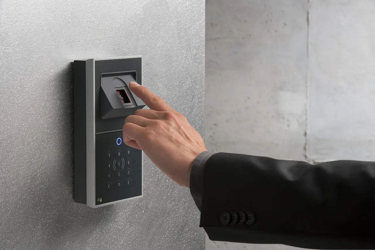 A finger pressing the reader on a wall-mounted fingerprint access panel