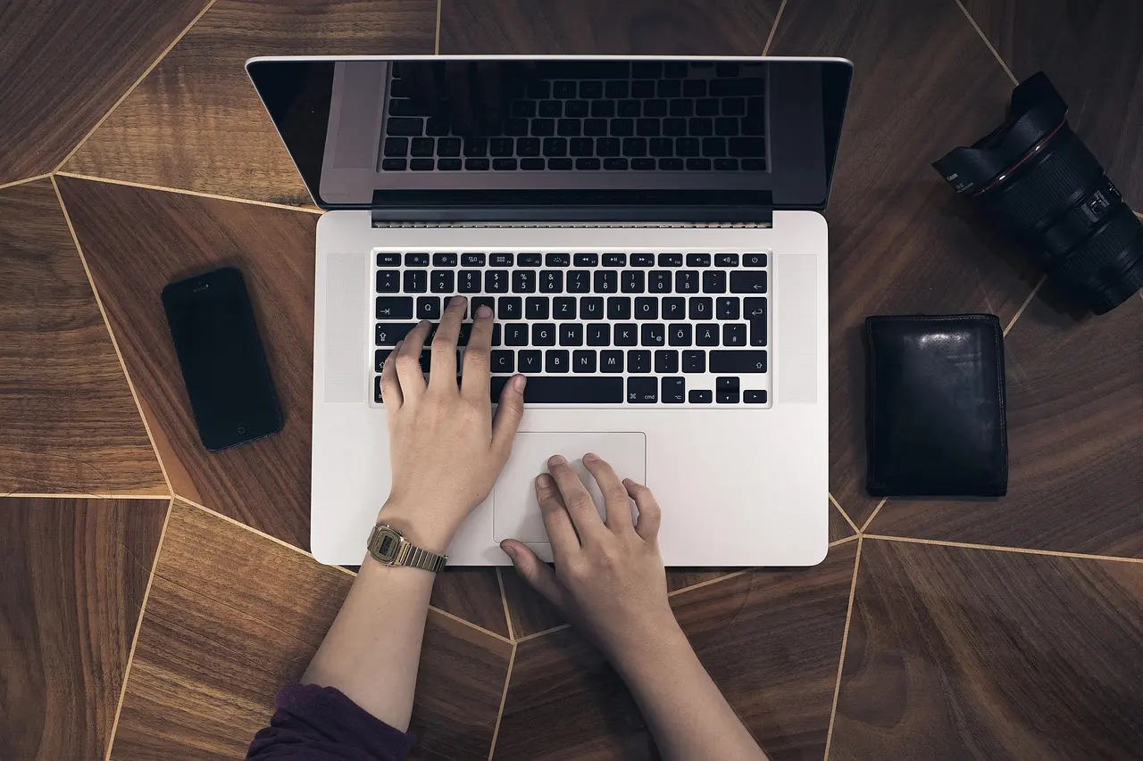 A laptop and a phone in a person's hands