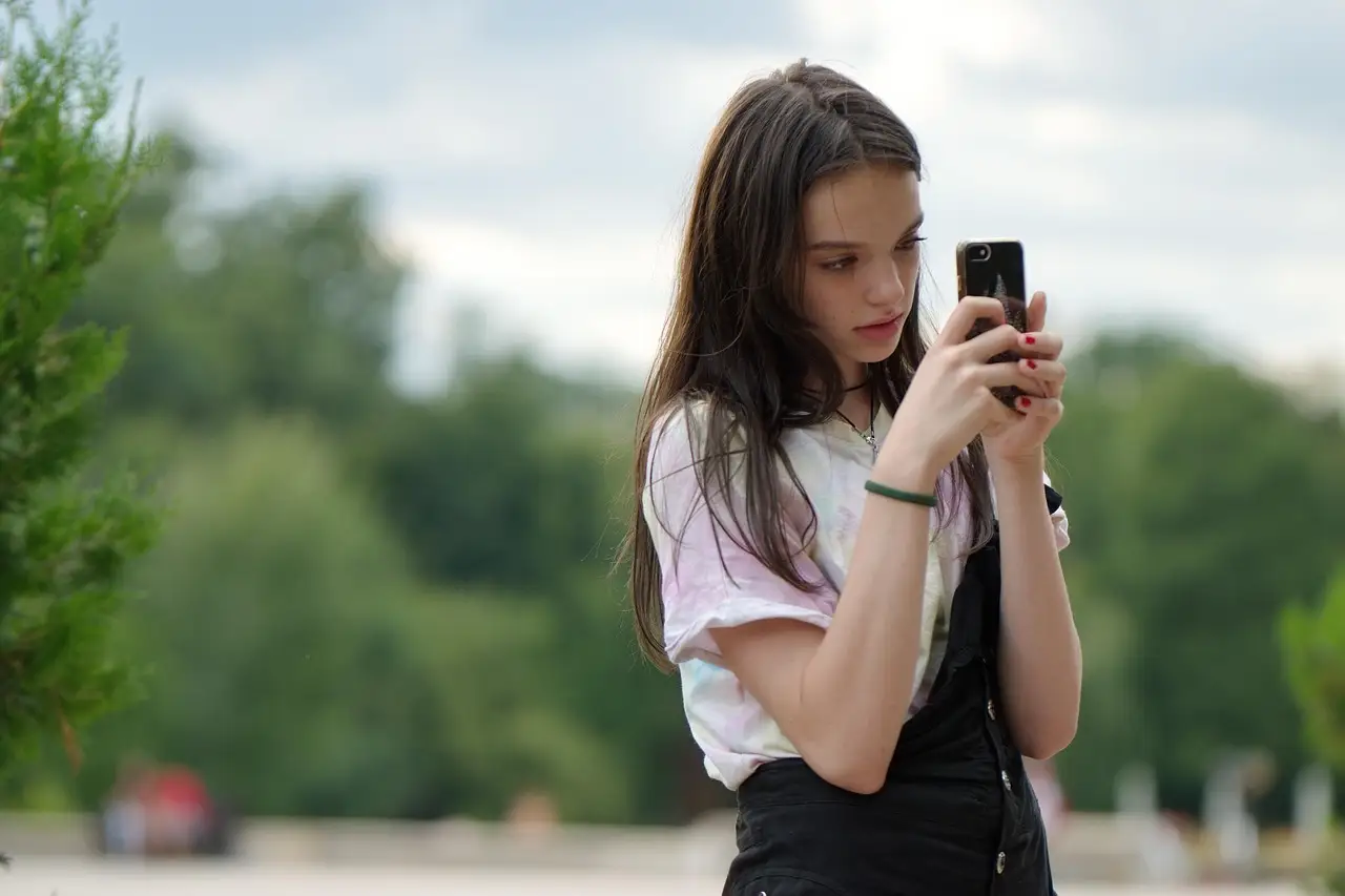 A hand holding a smartphone showing a photo gallery