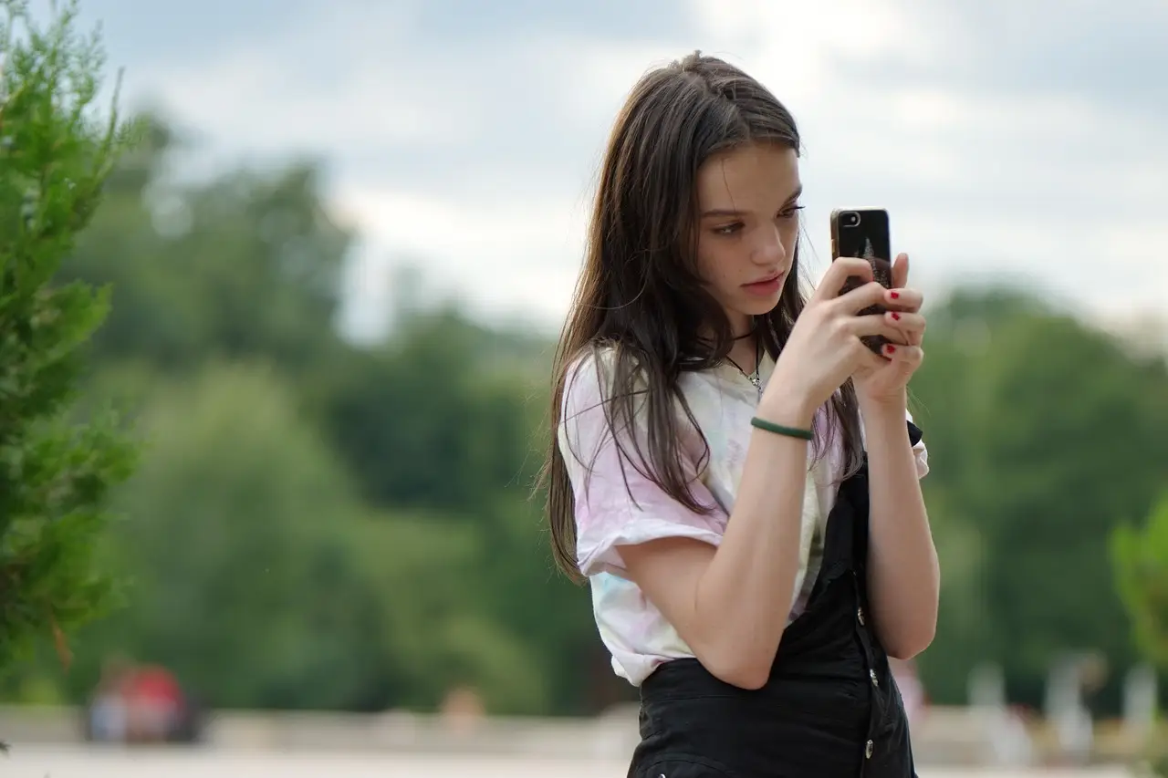 A hand holding a smartphone showing a photo gallery