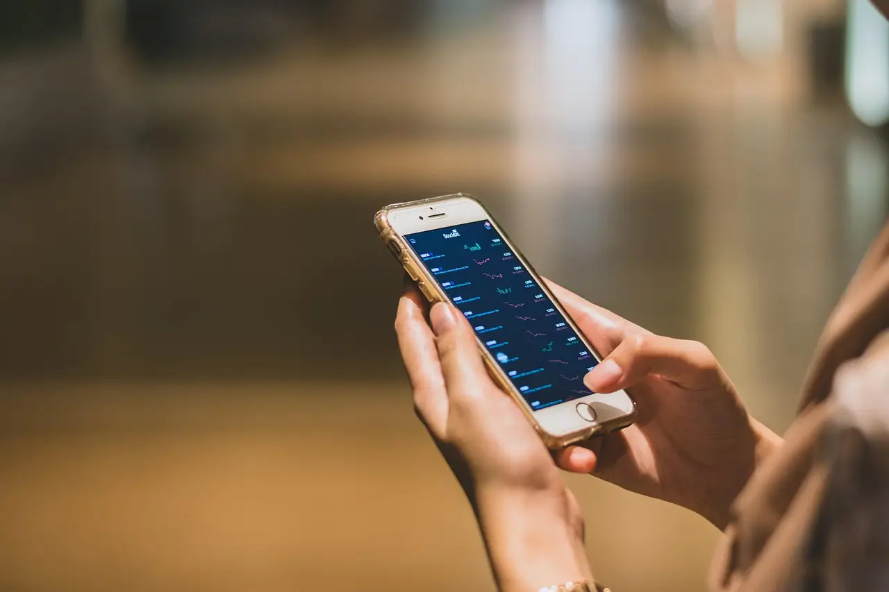 Two hands holding an Android phone above a desk