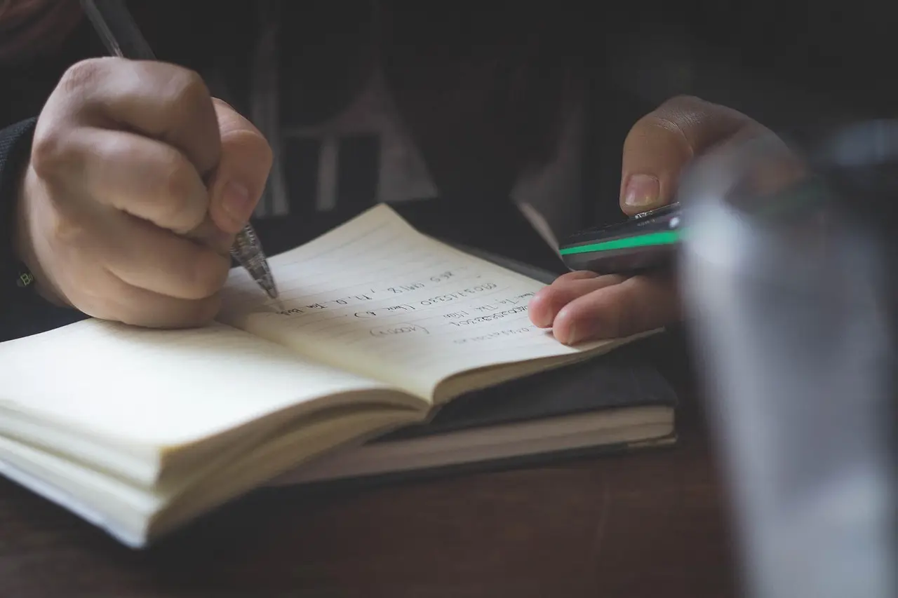 A hand editing text with a pen on a notebook