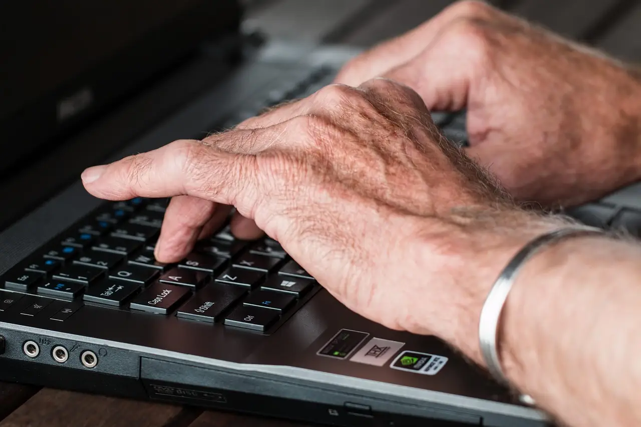 Close-up of a person's hands typing on a black Windows laptop keyboard