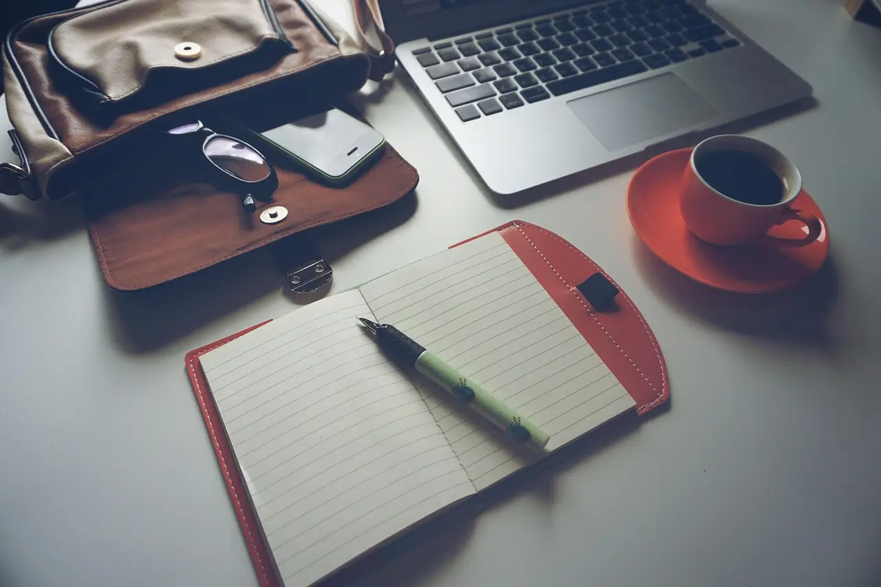 A laptop on a desk with coffee and glasses.
