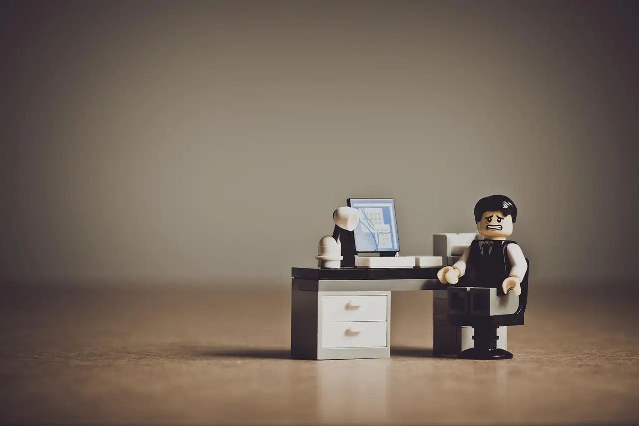 A frustrated person at a desk holding their head in their hands